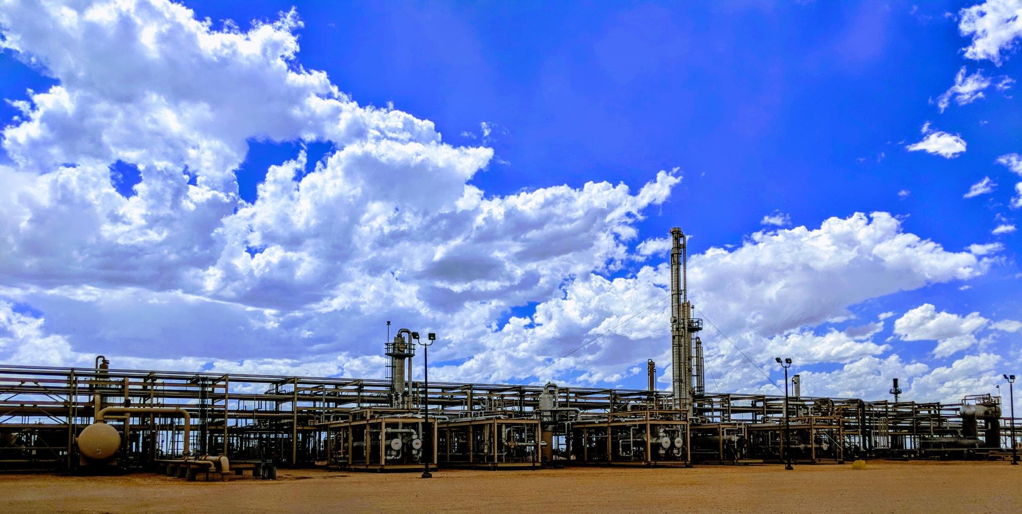 Oil and gas facility with pipeline infrastructure under a blue sky in the Permian Basin